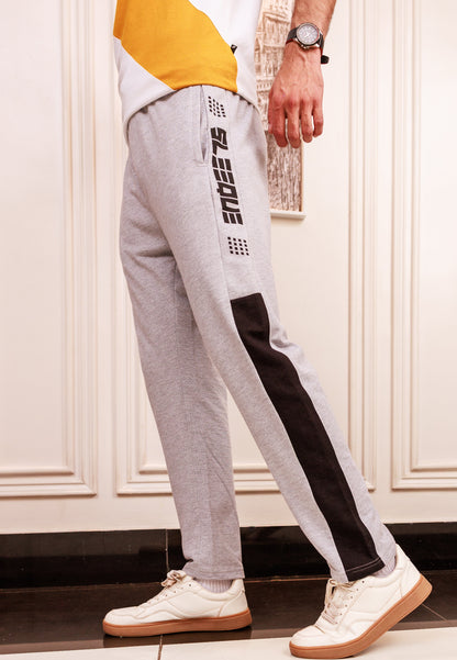 Person wearing gray and black jogger pants with a brand logo, standing indoors.