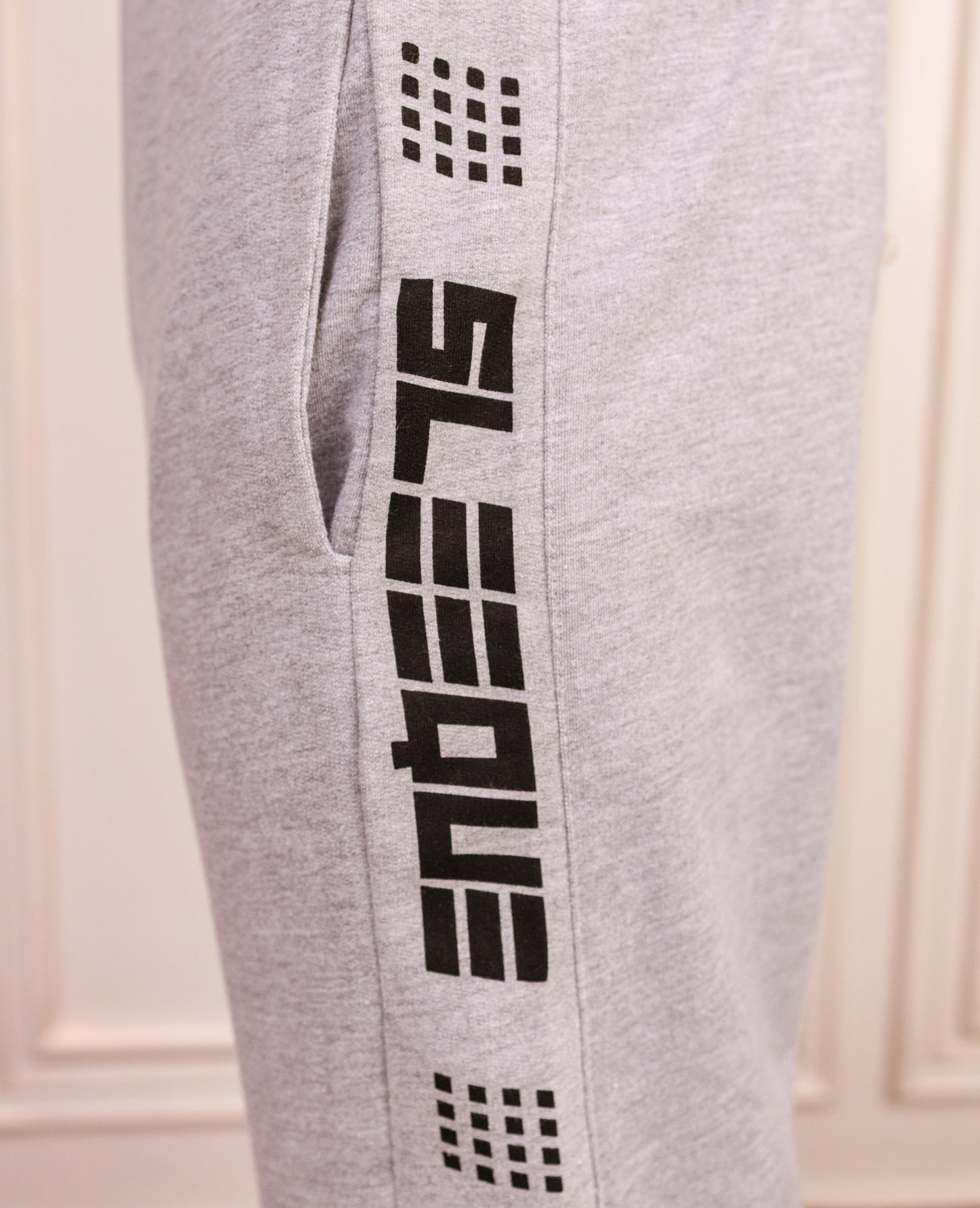 Gray sweatpants with black branding on a white background