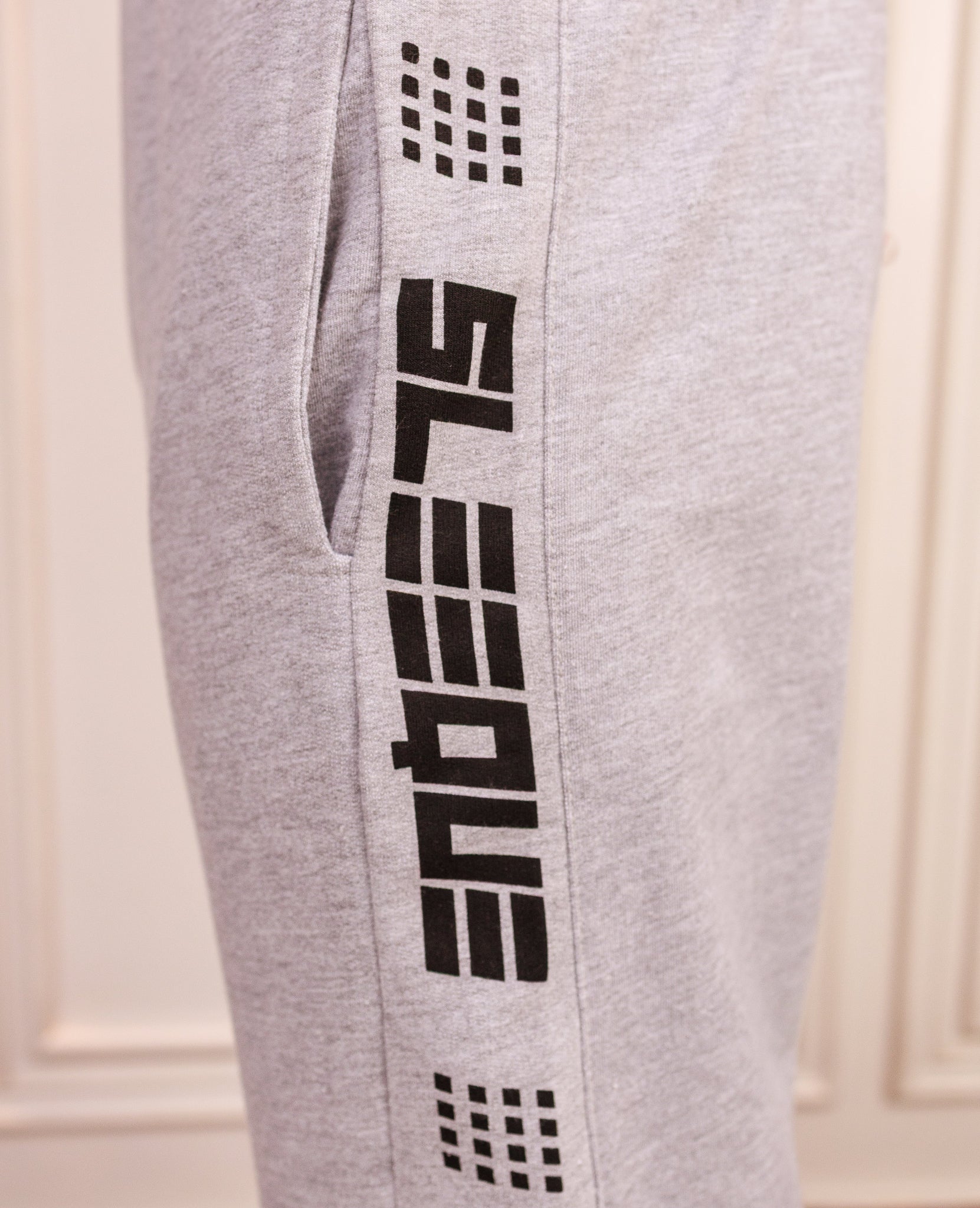 Gray sweatpants with black branding on a white background