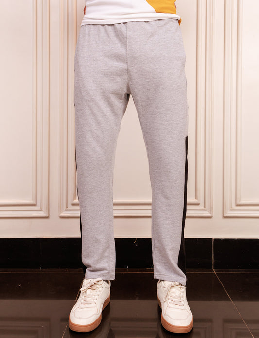 Person wearing gray sweatpants and white sneakers in a room with beige walls.