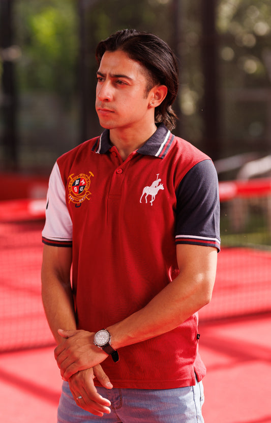 Man wearing a red polo shirt with a logo on a red surface