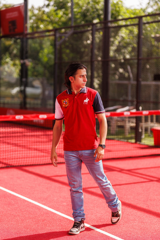 Person standing on a red sports court wearing a red and white shirt with a logo.