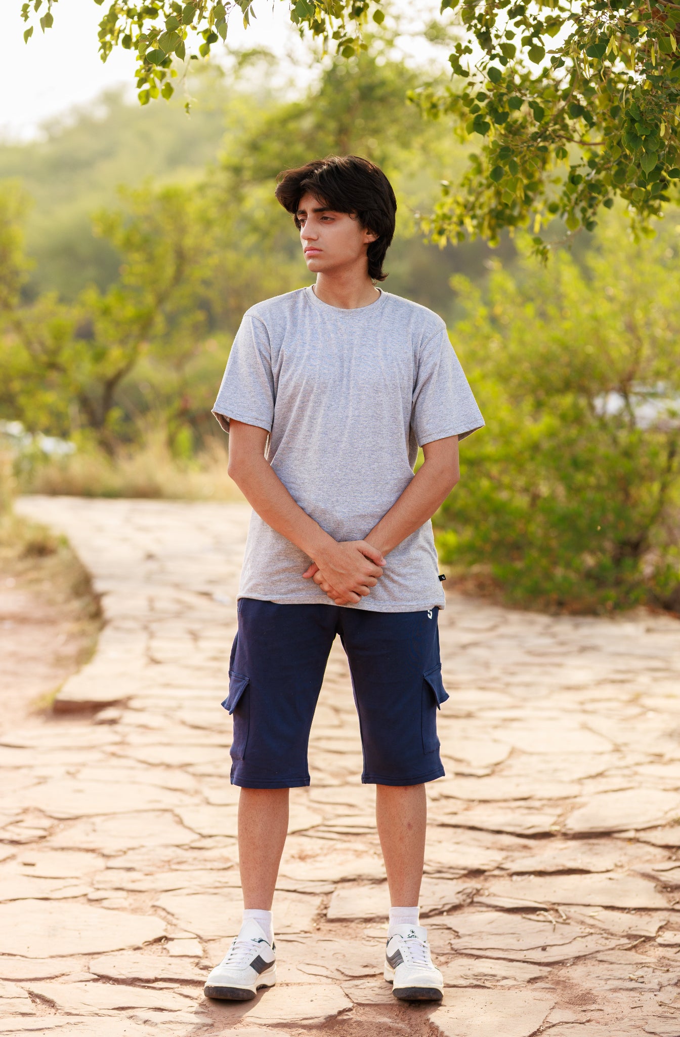 Person standing on a stone path with greenery in the background