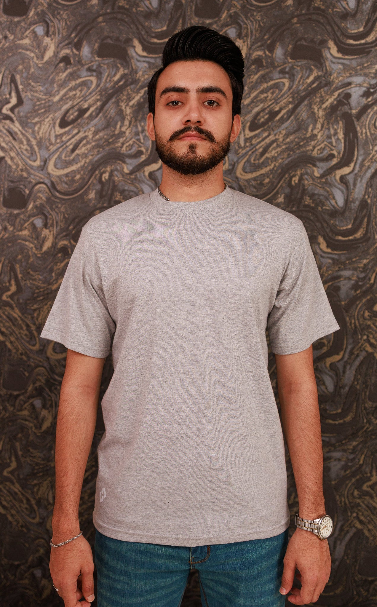 Man wearing a gray t-shirt against a marbled wall