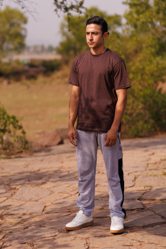 Man standing outdoors on a stone path with greenery in the background