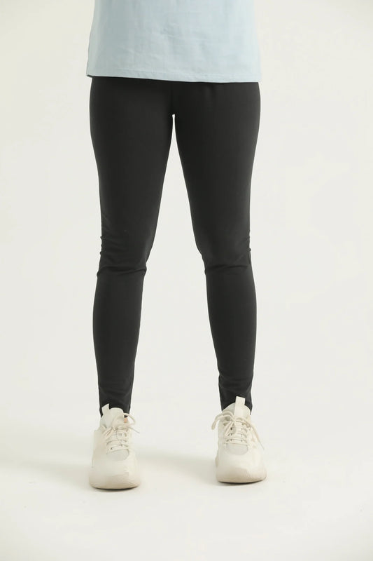A pair of black leggings on a female model, paired with a blue top and white sneakers.