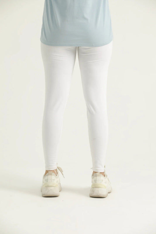 Person wearing a light blue top and white pants on a plain background