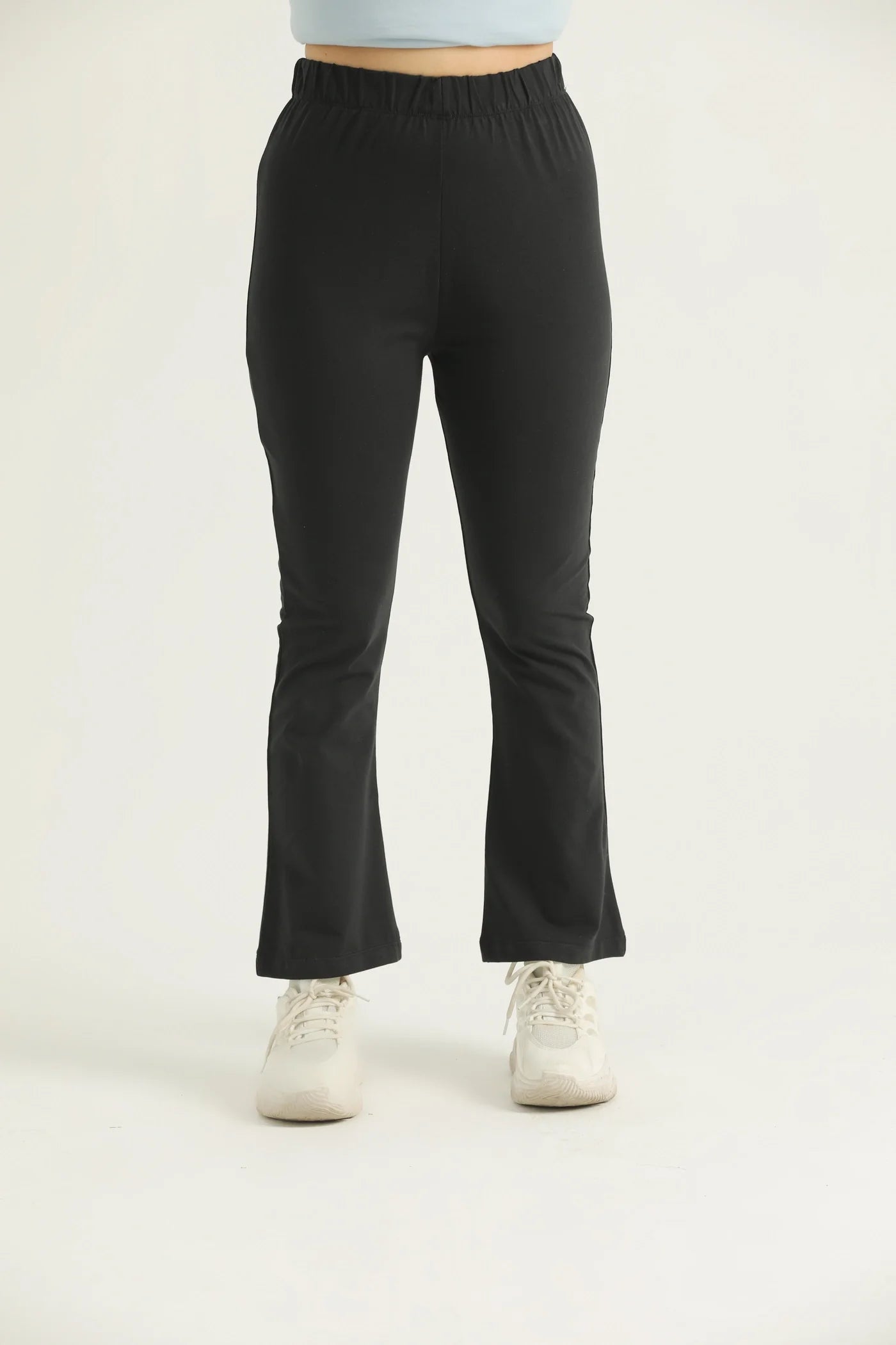 A pair of black flared leggings with a high waistband, modeled by a woman standing against a white background