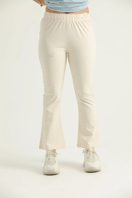 A pair of beige flared leggings with a high waistband, worn with white sneakers.