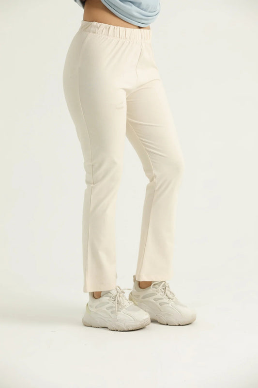 A pair of beige flared leggings with a high waistband, worn with white sneakers.