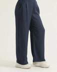 Navy blue flared trousers with a flat front and back elasticated waistband, pleats at the front, and cross pockets.