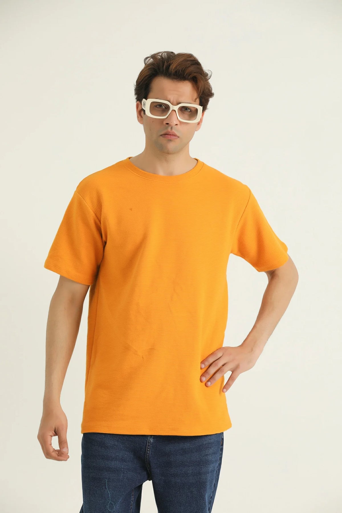 A male model wearing a yellow loose fit t-shirt with a rib-trimmed neckline, dropped shoulders, and a straight-cut hem.