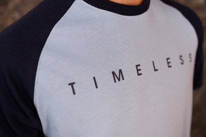 Person wearing a black and gray baseball shirt with 'TIMELESS' text.