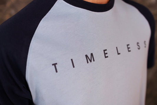 Person wearing a black and gray baseball shirt with 'TIMELESS' text.