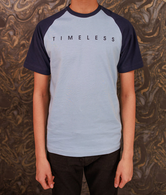 Person wearing a blue and navy 'TIMELESS' t-shirt against a patterned background