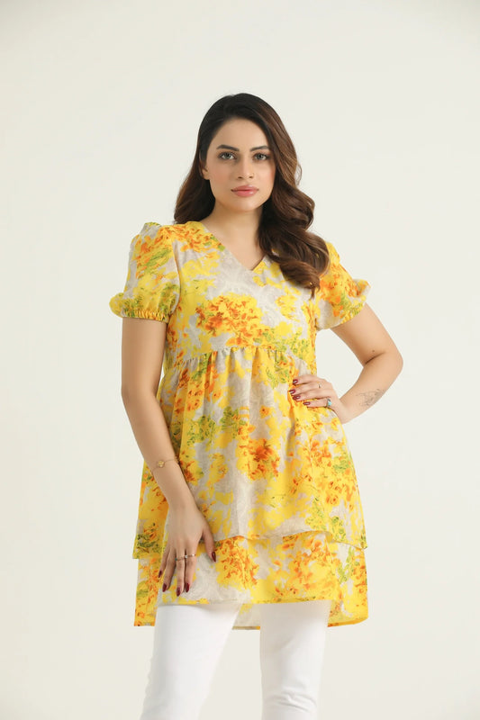 A mid-length floral-printed tunic in marigold yellow with orange and white flowers, featuring a V-neckline, short elasticated sleeves, and a double-tiered hemline.