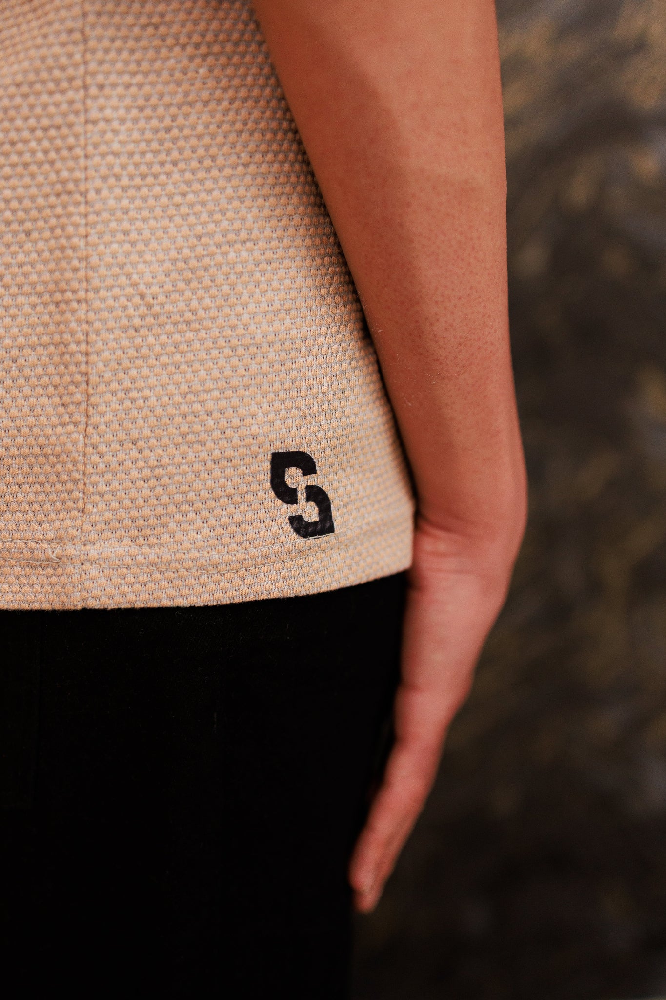 Close-up of a textured beige garment with a black logo on a blurred background