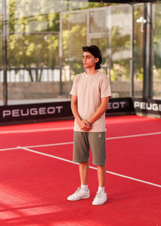 Person standing on a red sports court with 'Peugeot' branding in the background