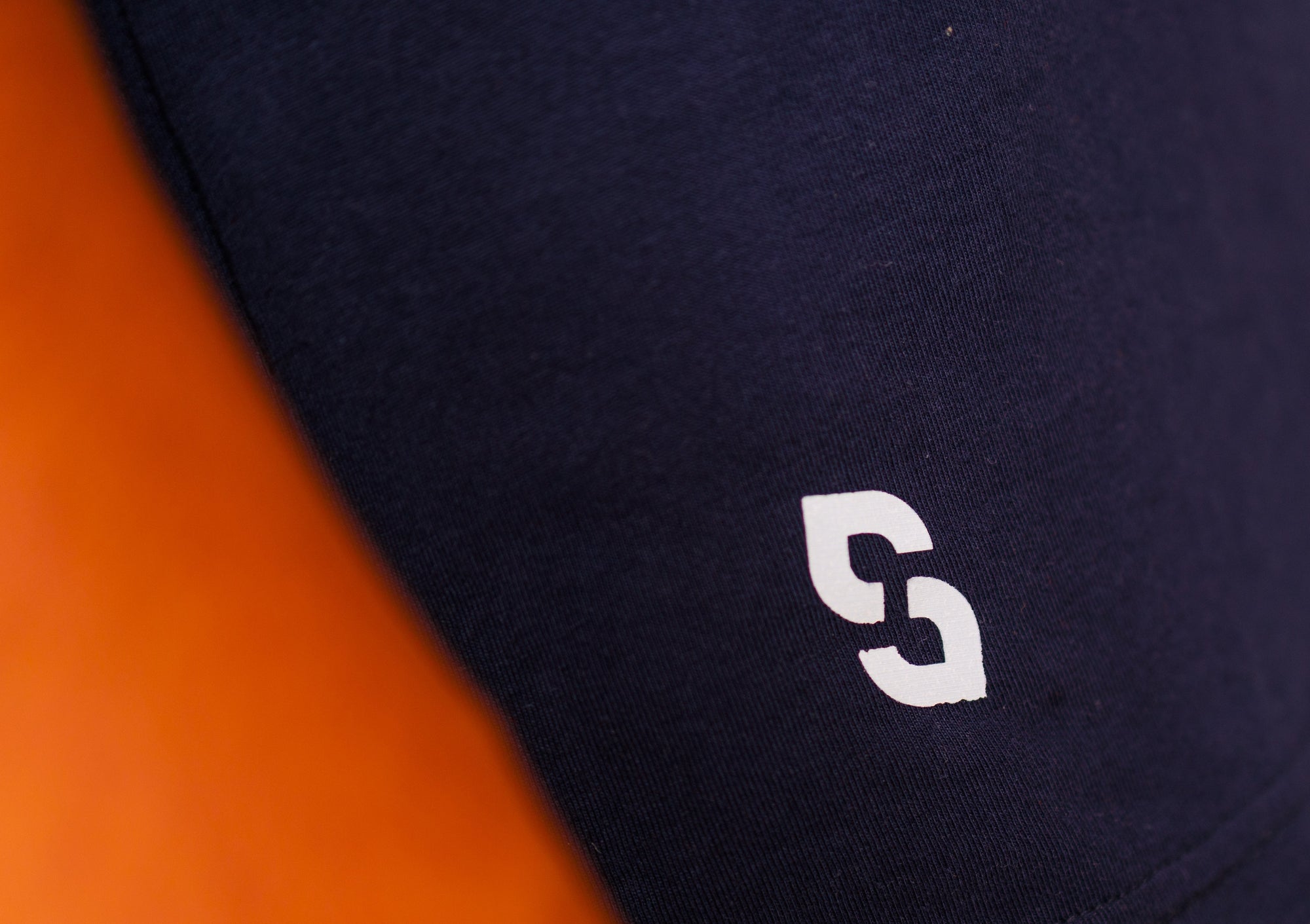 Close-up of a black shirt with a white logo on an orange background