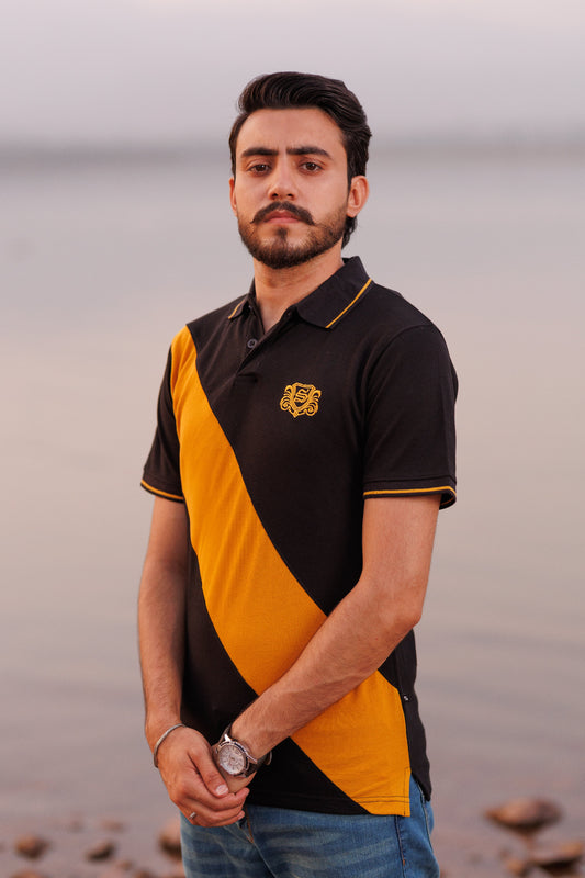 Man wearing a black and yellow polo shirt with a tiger logo on a beach.