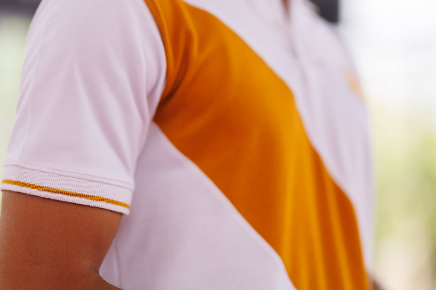 Close-up of a person wearing a white and orange sports jersey with blurred background