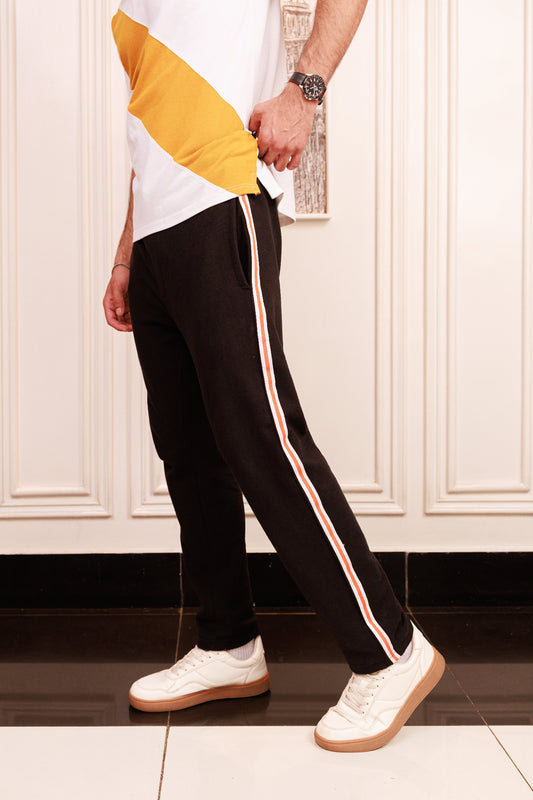 Person wearing black pants with white stripes and white sneakers in a kitchen setting