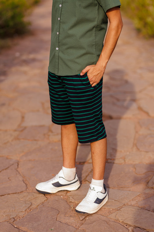Person wearing a green shirt and striped shorts on a stone path