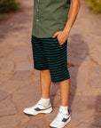 Person wearing a green shirt and striped shorts on a stone path