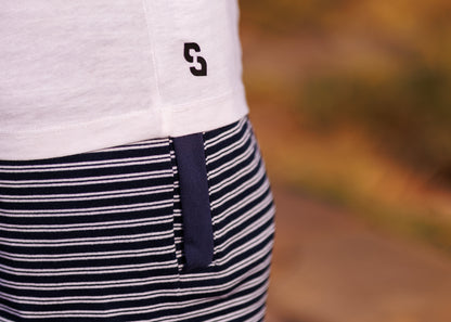 Close-up of a person wearing a white shirt with a logo and a black and white striped apron.