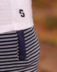 Close-up of a person wearing a white shirt with a logo and a black and white striped apron.