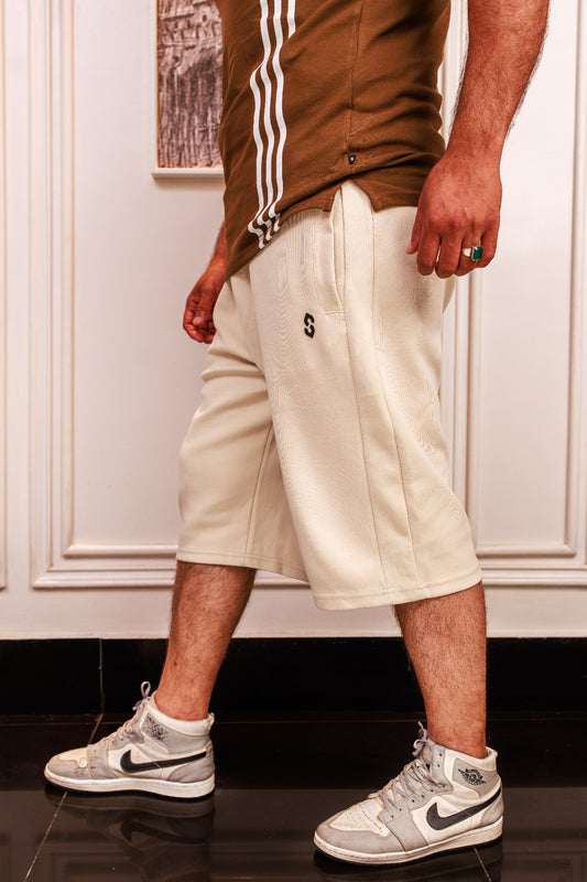 Person wearing beige shorts, brown shirt with white stripes, and white Nike sneakers indoors.