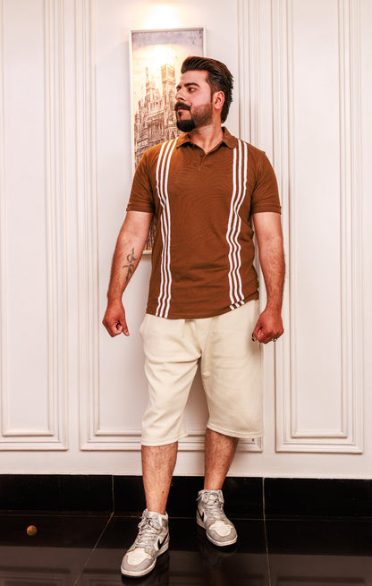 Man wearing a brown polo shirt with white stripes and beige shorts indoors.