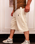 Person wearing beige shorts, brown shirt with white stripes, and white Nike sneakers indoors.