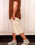 Person wearing a brown shirt, beige shorts, and white sneakers with black Nike logos.