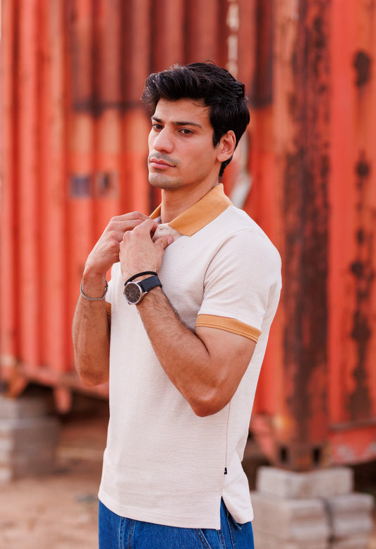 Man adjusting his collar in front of orange shipping containers