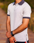 Man wearing a patterned polo shirt with a blurred natural background
