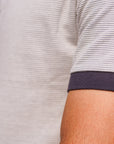 Close-up of a person wearing a light gray shirt with dark blue cuffs.
