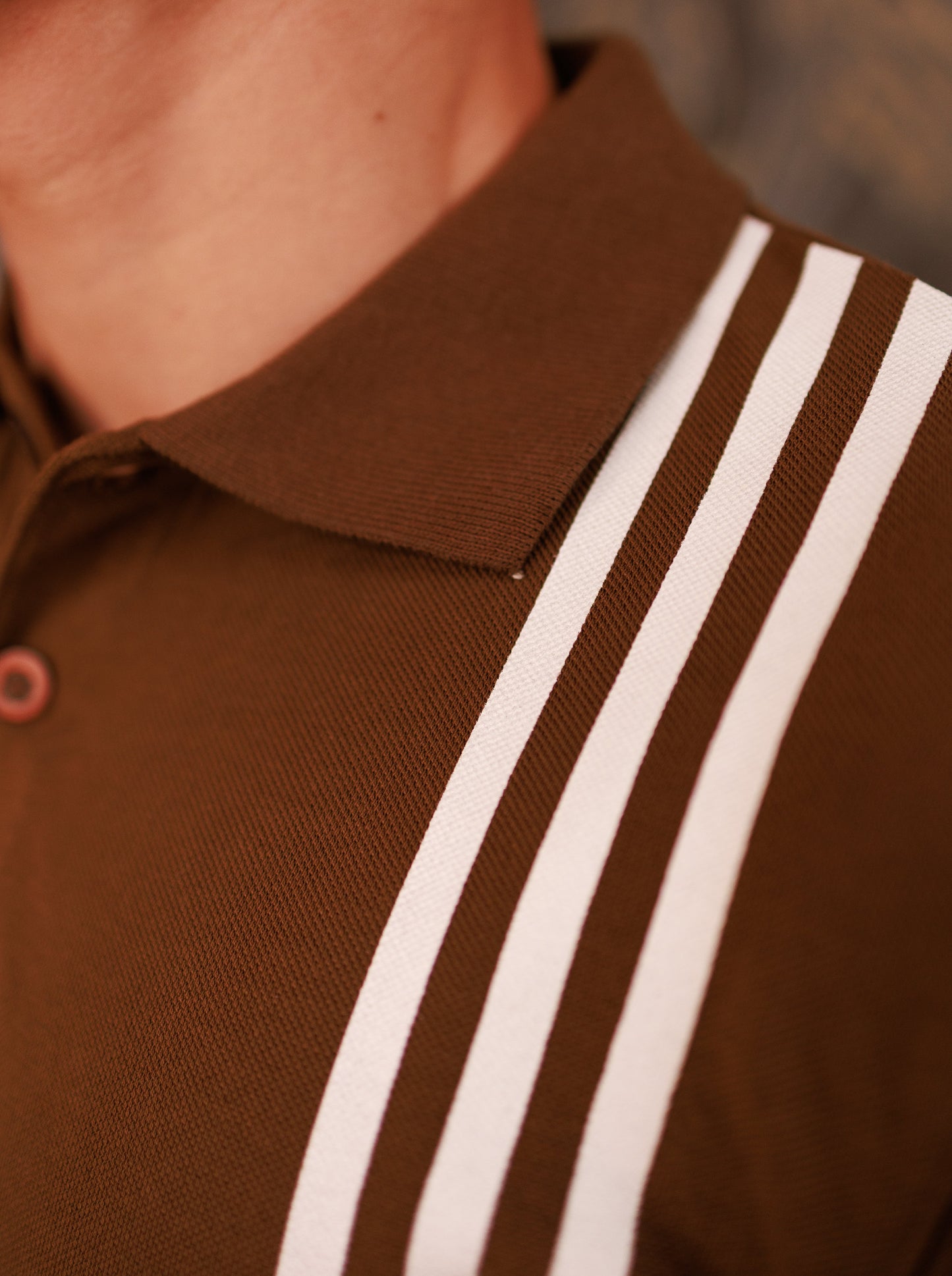 Brown polo shirt with white stripes on a blurred background