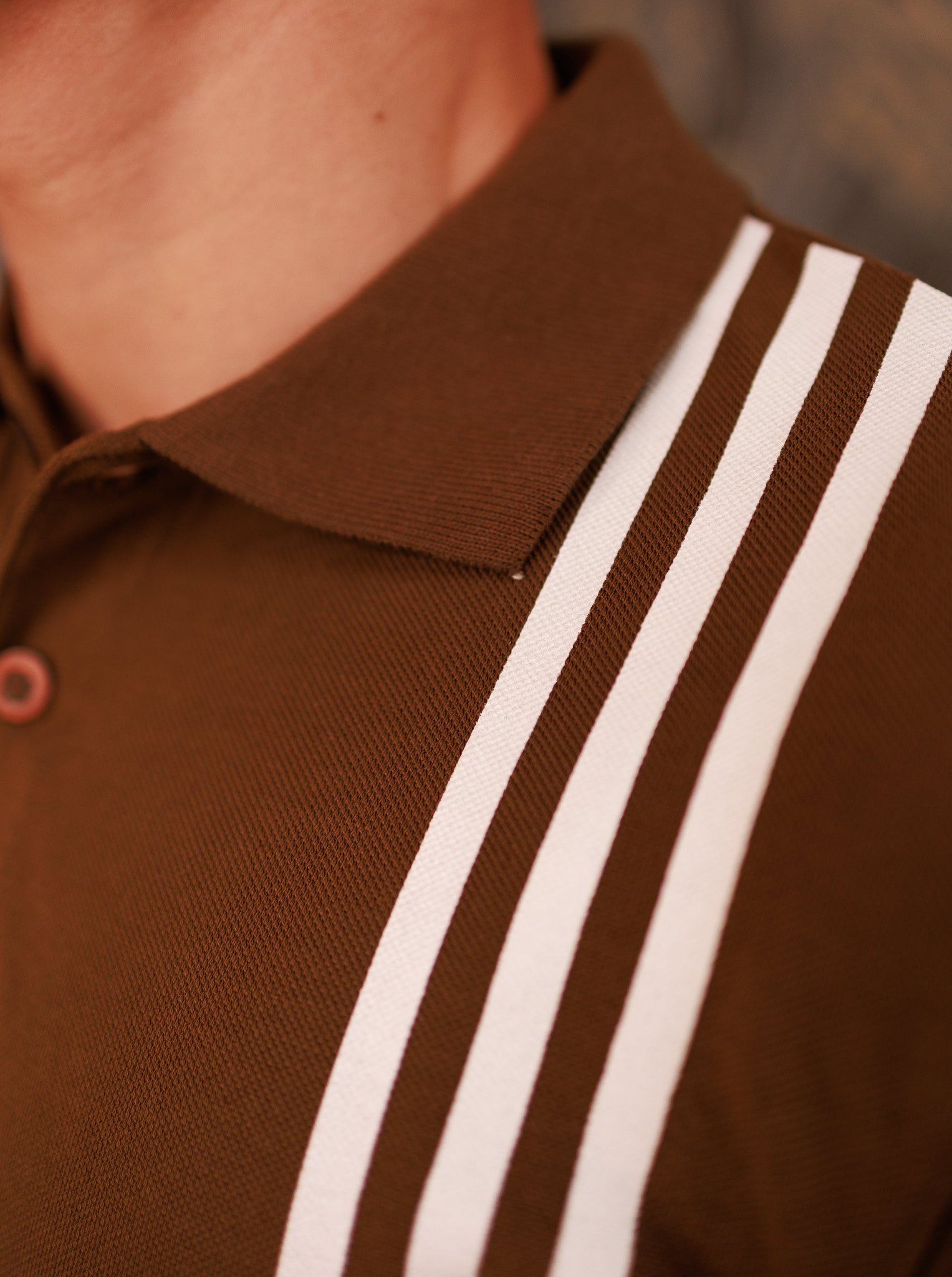 Brown polo shirt with white stripes on a blurred background