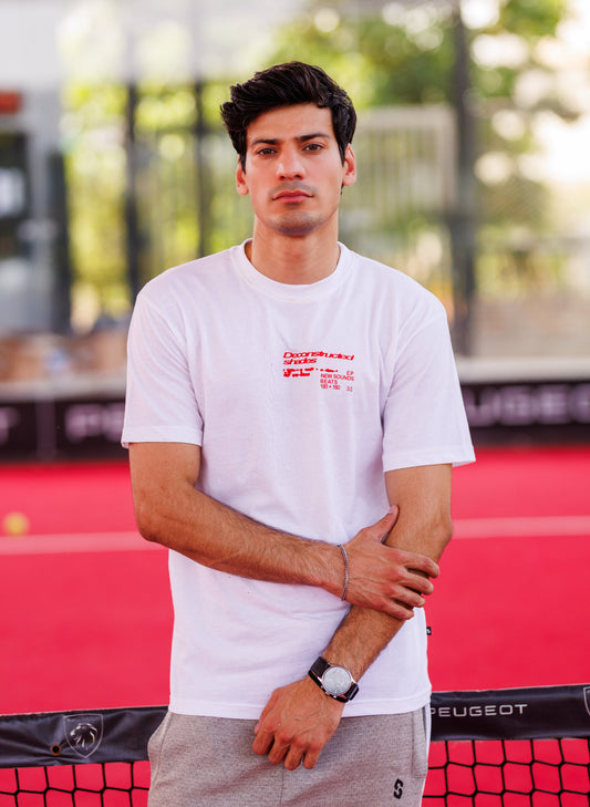 Man wearing a white t-shirt with red text standing in front of a red and black background