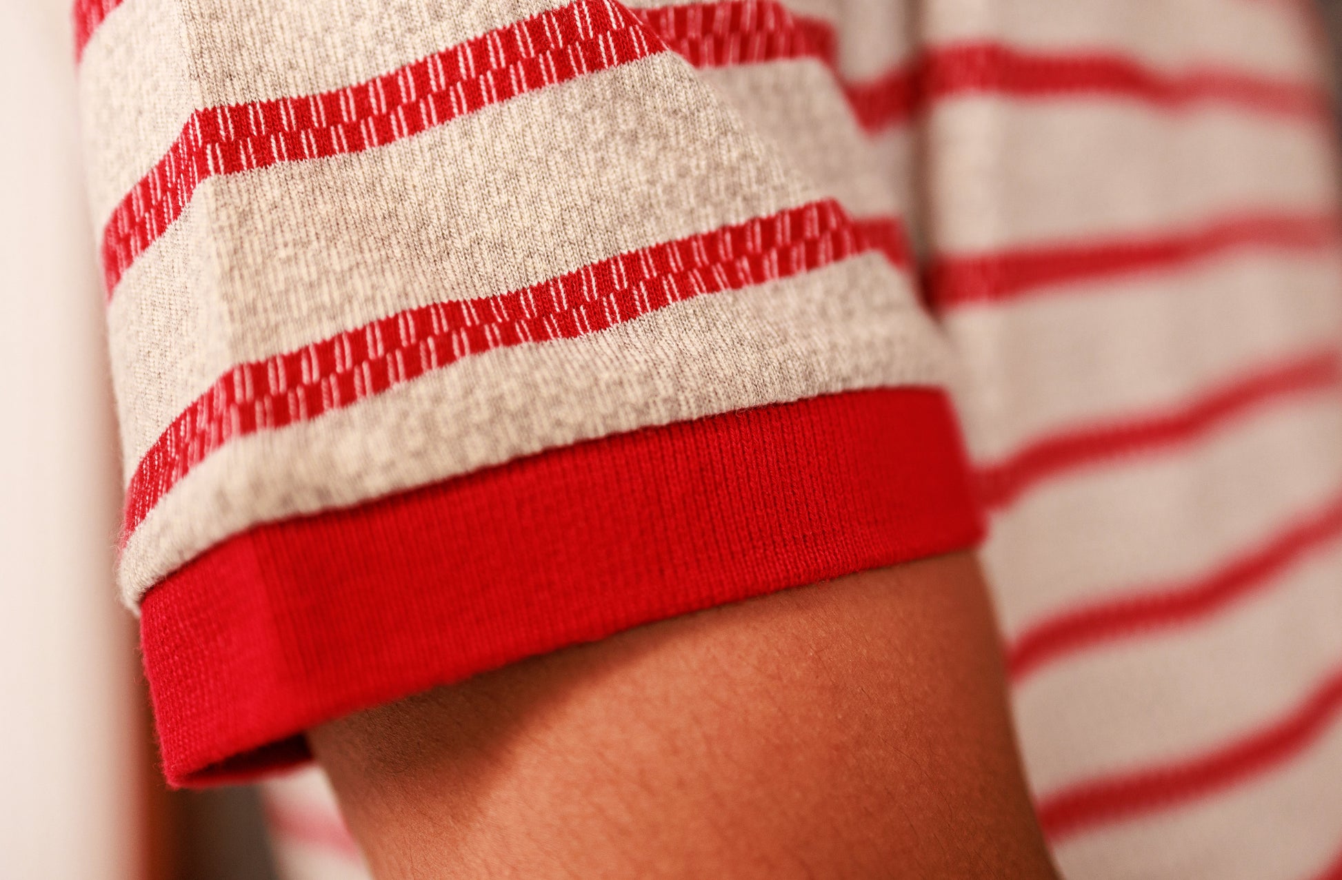 Close-up of a person wearing a red and white striped shirt with rolled-up sleeves.