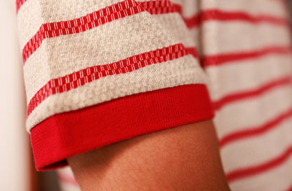 Close-up of a person wearing a red and white striped shirt with rolled-up sleeves.