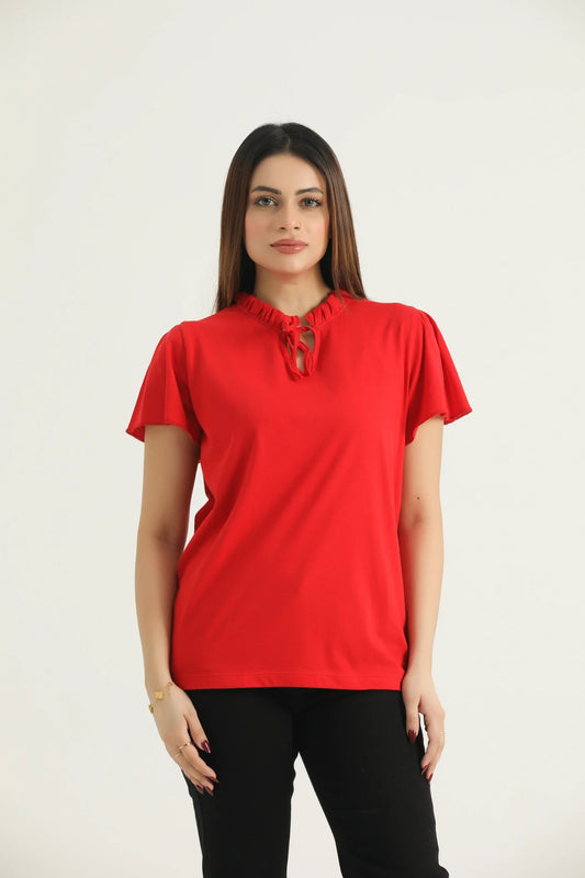 A woman wearing a red frill knit top with a round neckline, frill cap sleeves, and a drawstring detail at the front.